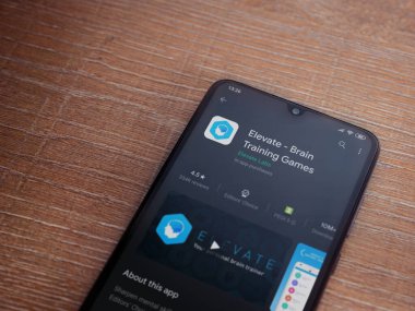 Lod, Israel - 8 Temmuz 2020: Ahşap arka planda siyah bir cep telefonunun sergilendiği Beyin Eğitim Oyunları uygulamaları oyun mağazası sayfası. Üst görünüm düzlüğü kopyalama alanı ile yatıyordu.
