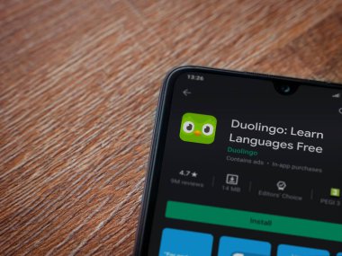 Lod, Israel - 8 Temmuz 2020: Duolingo - Dil öğrenme uygulaması oyun sayfası ahşap arka planda siyah bir cep telefonu ekranında. Üst görünüm düzlüğü kopyalama alanı ile yatıyordu.