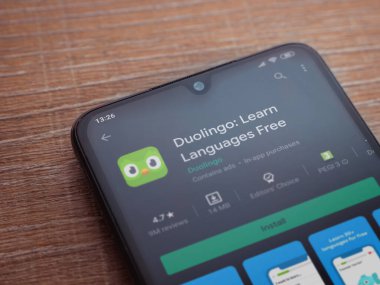 Lod, Israel - 8 Temmuz 2020: Duolingo - Dil öğrenme uygulaması oyun sayfası ahşap arka planda siyah bir cep telefonu ekranında. Üst görünüm düzlüğü kopyalama alanı ile yatıyordu.