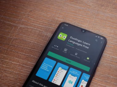 Lod, Israel - 8 Temmuz 2020: Duolingo - Dil öğrenme uygulaması oyun sayfası ahşap arka planda siyah bir cep telefonu ekranında. Üst görünüm düzlüğü kopyalama alanı ile yatıyordu.