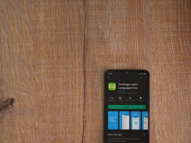 Lod, Israel - 8 Temmuz 2020: Duolingo - Dil öğrenme uygulaması oyun sayfası ahşap arka planda siyah bir cep telefonu ekranında. Üst görünüm düzlüğü kopyalama alanı ile yatıyordu.