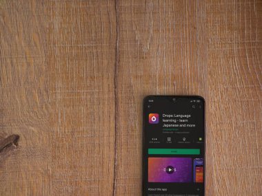Lod, Israel - 8 Temmuz 2020: Damlalar - Dil öğrenme uygulaması oyun mağazası sayfası ahşap arka planda siyah bir cep telefonunun ekranında. Üst görünüm düzlüğü kopyalama alanı ile yatıyordu.