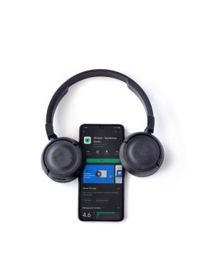 Lod, Israel - 8 Temmuz 2020: Blinkist uygulama oyun mağazası sayfası ve beyaz arka planda kablosuz kulaklıklı siyah cep telefonu. Üst görünüm düzlüğü kopyalama alanı ile yatıyordu.