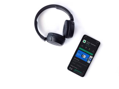 Lod, Israel - 8 Temmuz 2020: Blinkist uygulama oyun mağazası sayfası ve beyaz arka planda kablosuz kulaklıklı siyah cep telefonu. Üst görünüm düzlüğü kopyalama alanı ile yatıyordu.