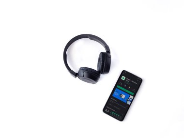 Lod, Israel - 8 Temmuz 2020: Blinkist uygulama oyun mağazası sayfası ve beyaz arka planda kablosuz kulaklıklı siyah cep telefonu. Üst görünüm düzlüğü kopyalama alanı ile yatıyordu.