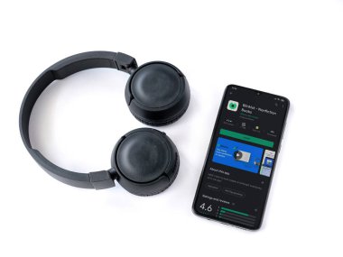 Lod, Israel - 8 Temmuz 2020: Blinkist uygulama oyun mağazası sayfası ve beyaz arka planda kablosuz kulaklıklı siyah cep telefonu. Üst görünüm düzlüğü kopyalama alanı ile yatıyordu.