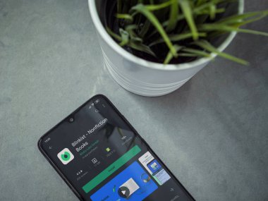 Lod, Israel - 8 Temmuz 2020: Blinkist uygulama oyun mağazası sayfası mermer arka planda siyah cep telefonlu modern minimalist ofis çalışma alanı. Üst görünüm yatağını kapat.