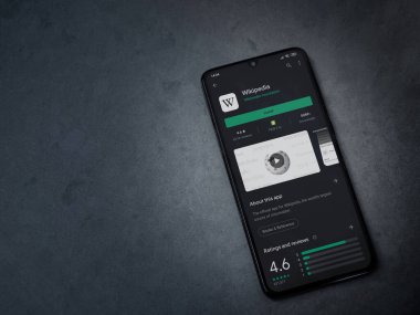 Lod, Israel - 8 Temmuz 2020: Wikipedia uygulama oyun mağazası sayfası koyu mermer taştan bir arka planda siyah bir cep telefonu ekranında. Üst görünüm düzlüğü kopyalama alanı ile yatıyordu.