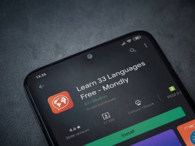 Lod, Israel - 8 Temmuz 2020: Mondlay - Dil öğrenme uygulaması oyun mağazası sayfası koyu mermer taştan bir arka planda siyah bir cep telefonu sergilenmektedir. Üst görünüm düzlüğü kopyalama alanı ile yatıyordu.