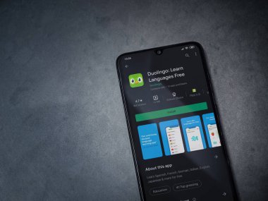 Lod, Israel - 8 Temmuz 2020: Duolingo - Dil öğrenme uygulaması oyun sayfası koyu mermer taşlı arka planda siyah bir cep telefonu sergilenmektedir. Üst görünüm düzlüğü kopyalama alanı ile yatıyordu.