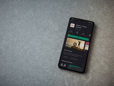 Lod, Israel - 8 Temmuz 2020: Seramik taş zemin üzerinde siyah bir cep telefonunun sergilendiği Udemy uygulaması oyun mağazası sayfası. Üst görünüm düzlüğü kopyalama alanı ile yatıyordu.