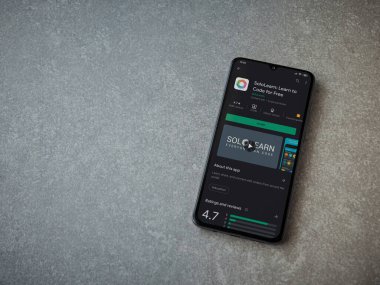 Lod, Israel - 8 Temmuz 2020: SoloLearn - Seramik taş zemin üzerinde siyah bir cep telefonunun ekranında kodlama uygulaması oyun mağazası sayfasını öğrenme. Üst görünüm düzlüğü kopyalama alanı ile yatıyordu.