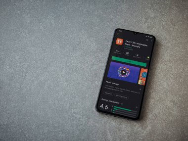 Lod, Israel - 8 Temmuz 2020: Mondlay - Seramik taş zemin üzerinde siyah bir cep telefonunun sergilendiği uygulama oyun mağazası sayfası. Üst görünüm düzlüğü kopyalama alanı ile yatıyordu.