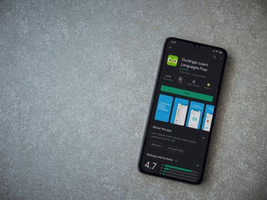 Lod, Israel - 8 Temmuz 2020: Duolingo - Seramik taş zemin üzerinde siyah bir cep telefonunun sergilendiği uygulama oyun mağazası sayfası. Üst görünüm düzlüğü kopyalama alanı ile yatıyordu.