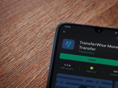 Lod, Israel - 8 Temmuz 2020: TransferWise uygulama oyun mağazası sayfası ahşap arka planda siyah bir cep telefonunun ekranında. Üst görünüm düzlüğü kopyalama alanı ile yatıyordu.