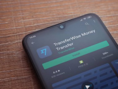 Lod, Israel - 8 Temmuz 2020: TransferWise uygulama oyun mağazası sayfası ahşap arka planda siyah bir cep telefonunun ekranında. Üst görünüm düzlüğü kopyalama alanı ile yatıyordu.