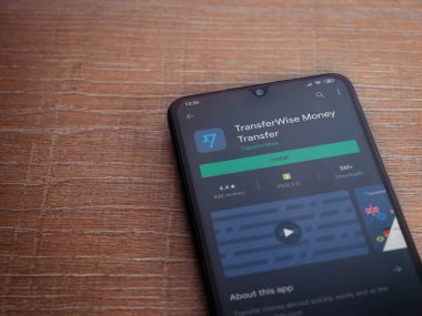 Lod, Israel - 8 Temmuz 2020: TransferWise uygulama oyun mağazası sayfası ahşap arka planda siyah bir cep telefonunun ekranında. Üst görünüm düzlüğü kopyalama alanı ile yatıyordu.