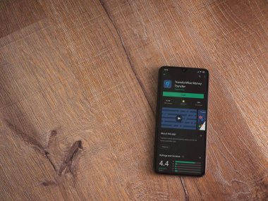 Lod, Israel - 8 Temmuz 2020: TransferWise uygulama oyun mağazası sayfası ahşap arka planda siyah bir cep telefonunun ekranında. Üst görünüm düzlüğü kopyalama alanı ile yatıyordu.