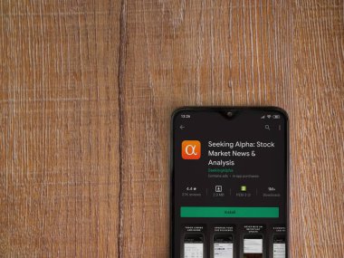 Lod, Israel - 8 Temmuz 2020: Tahta arka planda siyah bir cep telefonunun ekranında Alfa uygulaması oyun mağazası sayfası aranıyor. Üst görünüm düzlüğü kopyalama alanı ile yatıyordu.