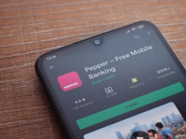 Lod, Israel - 8 Temmuz 2020: Biber uygulaması oyun mağazası sayfası ahşap arka planda siyah bir cep telefonunun ekranında. Üst görünüm düzlüğü kopyalama alanı ile yatıyordu.