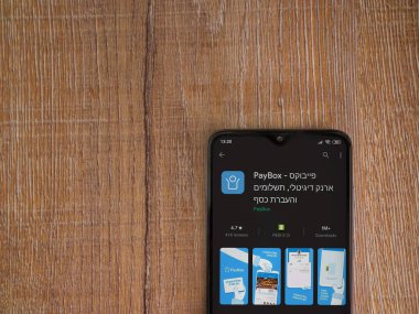 Lod, Israel - 8 Temmuz 2020: PayBox uygulaması oyun mağazası sayfası ahşap arka planda siyah bir cep telefonunun ekranında. Üst görünüm düzlüğü kopyalama alanı ile yatıyordu.