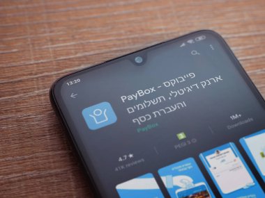 Lod, Israel - 8 Temmuz 2020: PayBox uygulaması oyun mağazası sayfası ahşap arka planda siyah bir cep telefonunun ekranında. Üst görünüm düzlüğü kopyalama alanı ile yatıyordu.