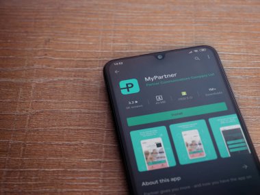 Lod, Israel - 8 Temmuz 2020: Partner Uygulama Oyun Mağazası sayfam ahşap arka planda siyah bir cep telefonunun ekranında. Üst görünüm düzlüğü kopyalama alanı ile yatıyordu.