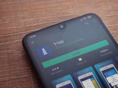 Lod, Israel - 8 Temmuz 2020: Gögdal uygulama oyun mağazası sayfası ahşap arka planda siyah bir cep telefonunun ekranında. Üst görünüm düzlüğü kopyalama alanı ile yatıyordu.
