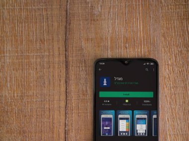 Lod, Israel - 8 Temmuz 2020: Gögdal uygulama oyun mağazası sayfası ahşap arka planda siyah bir cep telefonunun ekranında. Üst görünüm düzlüğü kopyalama alanı ile yatıyordu.