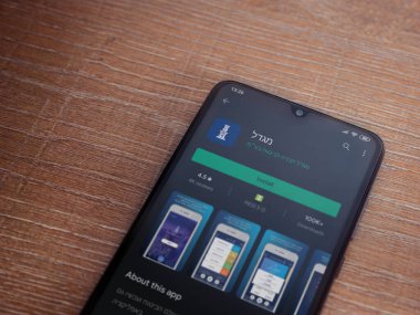 Lod, Israel - 8 Temmuz 2020: Gögdal uygulama oyun mağazası sayfası ahşap arka planda siyah bir cep telefonunun ekranında. Üst görünüm düzlüğü kopyalama alanı ile yatıyordu.