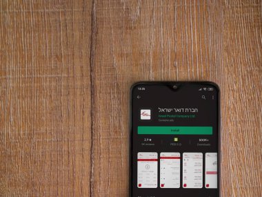 Lod, Israel - 8 Temmuz 2020: İsrail Postası uygulama oyun mağazası sayfası ahşap arka planda siyah bir cep telefonunun ekranında. Üst görünüm düzlüğü kopyalama alanı ile yatıyordu.