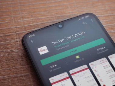 Lod, Israel - 8 Temmuz 2020: İsrail Postası uygulama oyun mağazası sayfası ahşap arka planda siyah bir cep telefonunun ekranında. Üst görünüm düzlüğü kopyalama alanı ile yatıyordu.