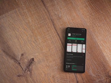 Lod, Israel - 8 Temmuz 2020: İsrail Postası uygulama oyun mağazası sayfası ahşap arka planda siyah bir cep telefonunun ekranında. Üst görünüm düzlüğü kopyalama alanı ile yatıyordu.