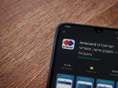Lod, Israel - 8 Temmuz 2020: Isracard uygulama oyun mağazası sayfası ahşap arka planda siyah bir cep telefonu ekranında. Üst görünüm düzlüğü kopyalama alanı ile yatıyordu.