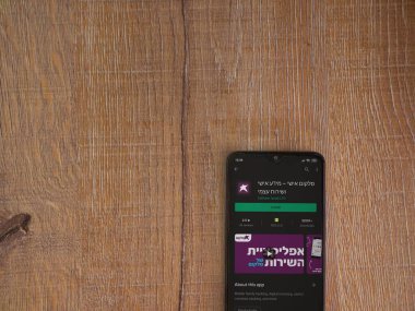 Lod, Israel - 8 Temmuz 2020: Cep telefonu uygulaması oyun mağazası sayfası ahşap arka planda siyah bir cep telefonunun ekranında. Üst görünüm düzlüğü kopyalama alanı ile yatıyordu.