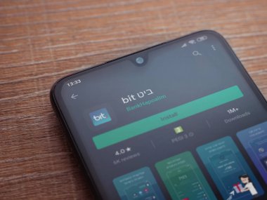 Lod, Israel - 8 Temmuz 2020: Ahşap arka planda siyah bir cep telefonunun ekranında bit uygulaması oyun mağazası sayfası. Üst görünüm düzlüğü kopyalama alanı ile yatıyordu.