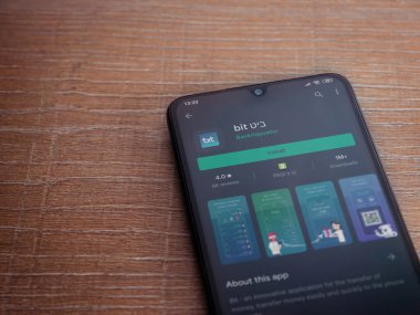 Lod, Israel - 8 Temmuz 2020: Ahşap arka planda siyah bir cep telefonunun ekranında bit uygulaması oyun mağazası sayfası. Üst görünüm düzlüğü kopyalama alanı ile yatıyordu.