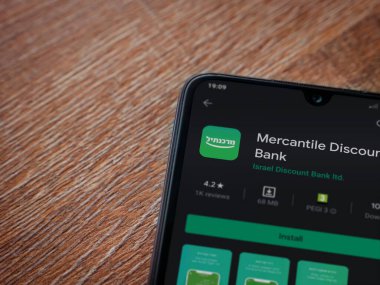 Lod, Israel - 8 Temmuz 2020: Bank Mercantil Discount uygulaması oyun mağazası sayfası ahşap arka planda siyah bir cep telefonu sergilenmektedir. Üst görünüm düzlüğü kopyalama alanı ile yatıyordu.