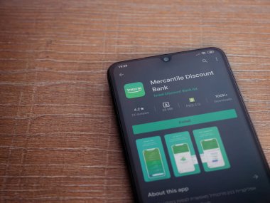 Lod, Israel - 8 Temmuz 2020: Bank Mercantil Discount uygulaması oyun mağazası sayfası ahşap arka planda siyah bir cep telefonu sergilenmektedir. Üst görünüm düzlüğü kopyalama alanı ile yatıyordu.