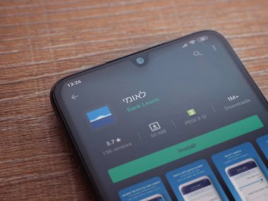 Lod, Israel - 8 Temmuz 2020: Bank Leumi uygulama oyun mağazası sayfası ahşap arka planda siyah bir cep telefonu ekranında. Üst görünüm düzlüğü kopyalama alanı ile yatıyordu.