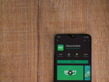 Lod, Israel - 8 Temmuz 2020: Banka İndirim uygulaması oyun mağazası sayfası ahşap arka planda siyah bir cep telefonunun ekranında. Üst görünüm düzlüğü kopyalama alanı ile yatıyordu.