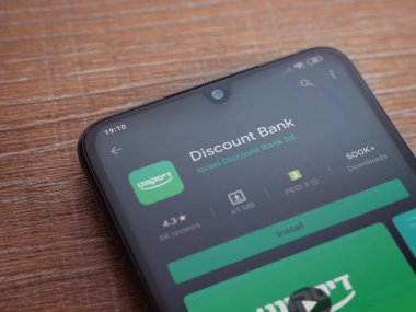 Lod, Israel - 8 Temmuz 2020: Banka İndirim uygulaması oyun mağazası sayfası ahşap arka planda siyah bir cep telefonunun ekranında. Üst görünüm düzlüğü kopyalama alanı ile yatıyordu.