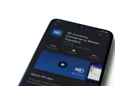 Lod, Israel - 8 Temmuz 2020: XE Para Birimi uygulaması oyun mağazası sayfası beyaz arkaplanda izole edilmiş siyah bir cep telefonu ekranında. Üst görünüm düzlüğü kopyalama alanı ile yatıyordu.