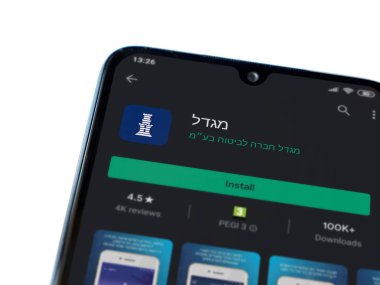 Lod, Israel - 8 Temmuz 2020: Migdal uygulaması oyun mağazası sayfası beyaz arka planda izole edilmiş siyah bir cep telefonu ekranında. Üst görünüm düzlüğü kopyalama alanı ile yatıyordu.