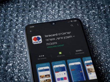 Lod, Israel - 8 Temmuz 2020: Metalik arka planda siyah bir cep telefonunun sergilendiği Isracard uygulama oyun mağazası sayfası. Üst görünüm yatağını kapat.