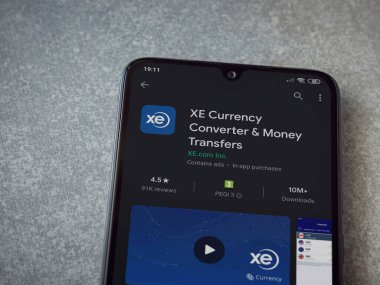 Lod, Israel - 8 Temmuz 2020: XE Para Birimi uygulaması oyun mağazası sayfası seramik taş zemin üzerinde siyah bir cep telefonu görüntüsü. Üst görünüm düzlüğü kopyalama alanı ile yatıyordu.