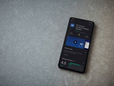 Lod, Israel - 8 Temmuz 2020: XE Para Birimi uygulaması oyun mağazası sayfası seramik taş zemin üzerinde siyah bir cep telefonu görüntüsü. Üst görünüm düzlüğü kopyalama alanı ile yatıyordu.