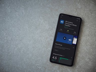 Lod, Israel - 8 Temmuz 2020: XE Para Birimi uygulaması oyun mağazası sayfası seramik taş zemin üzerinde siyah bir cep telefonu görüntüsü. Üst görünüm düzlüğü kopyalama alanı ile yatıyordu.