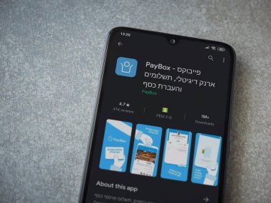 Lod, Israel - 8 Temmuz 2020: PayBox uygulaması oyun mağazası sayfası seramik taş zemin üzerinde siyah bir cep telefonu görüntüsü. Üst görünüm düzlüğü kopyalama alanı ile yatıyordu.