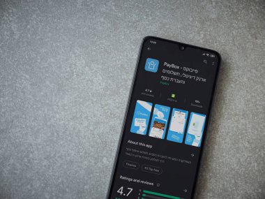 Lod, Israel - 8 Temmuz 2020: PayBox uygulaması oyun mağazası sayfası seramik taş zemin üzerinde siyah bir cep telefonu görüntüsü. Üst görünüm düzlüğü kopyalama alanı ile yatıyordu.